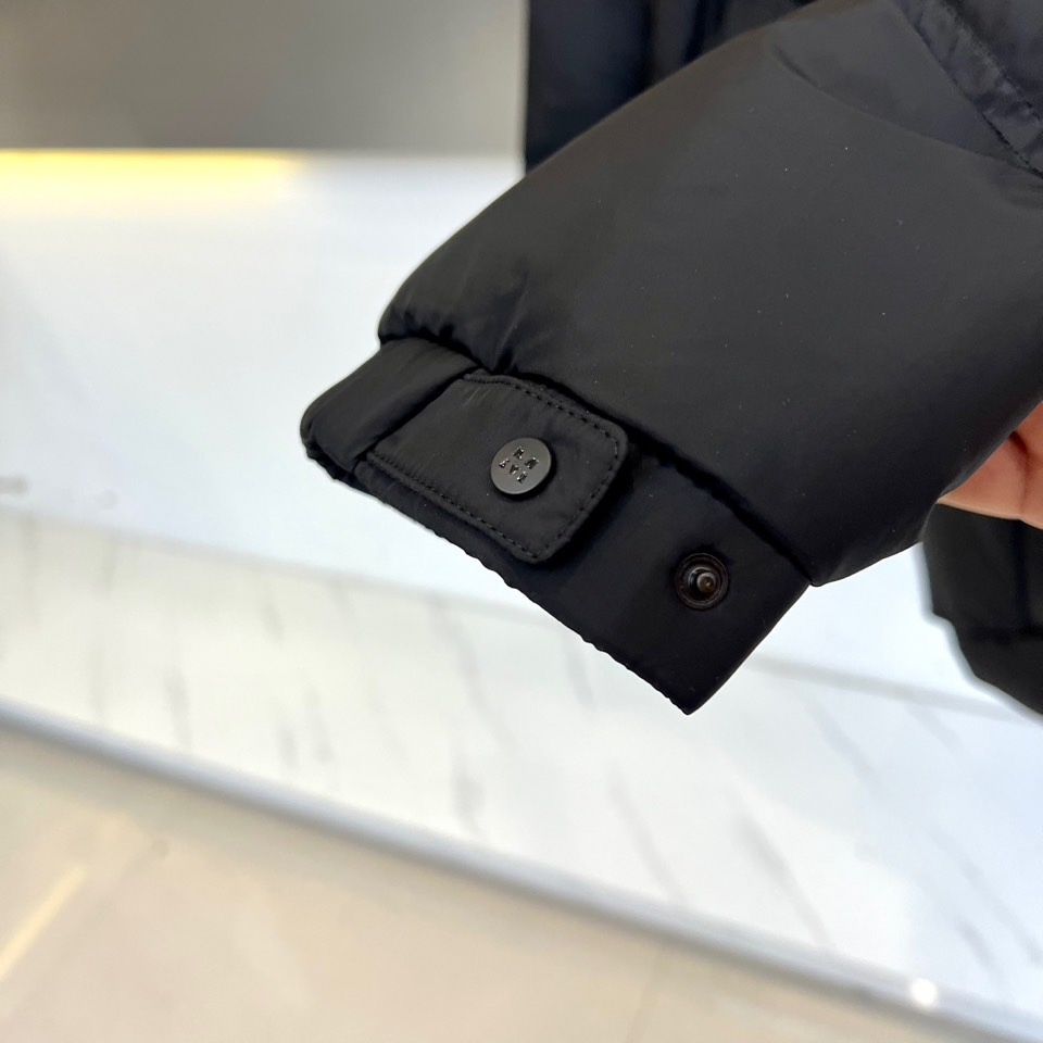 Mon蒙口（鹅绒）、2025秋冬新品黑色羽绒服，连帽设计搭配可调节防风系统，左袖饰有反光品牌徽章提升夜间