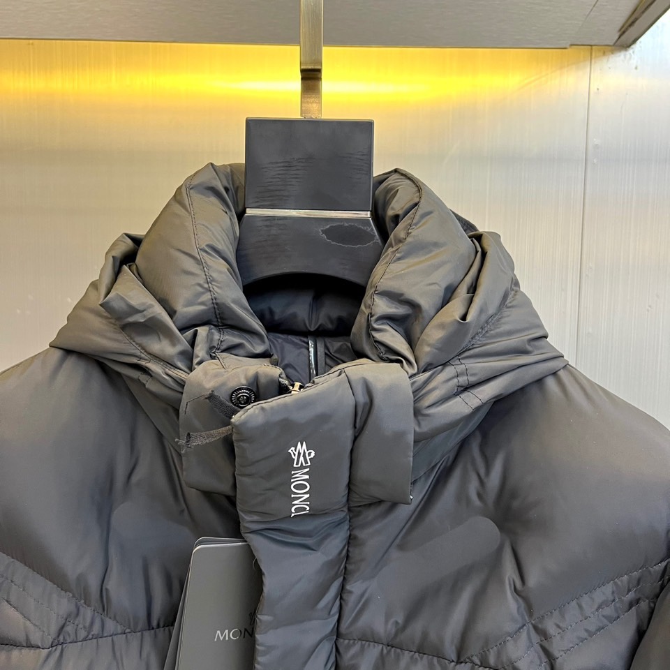 Mon蒙口（鹅绒）、2025秋冬新品黑色羽绒服，连帽设计搭配可调节防风系统，左袖饰有反光品牌徽章提升夜间