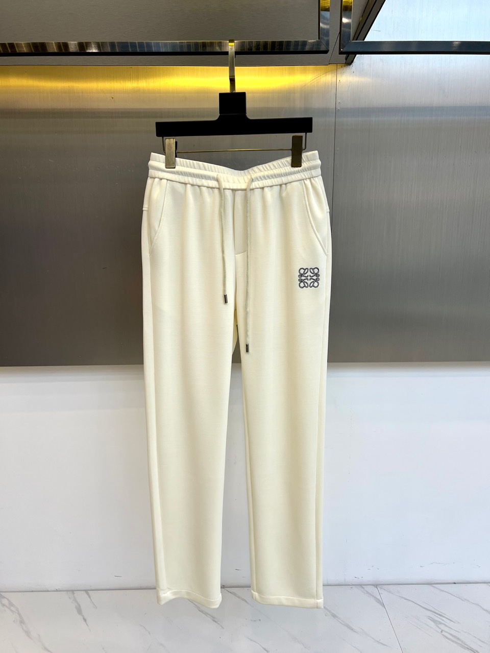 Lowe罗意威、2025秋冬新品休闲裤，以超柔面料重塑日常舒适的定义。本款采用柔和米白色调，呈现简约高级