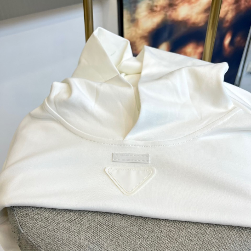 Prad普拉达、2025秋冬新品白色连帽上衣，以极简设计诠释现代奢华运动风范。款式采用宽松立体的剪裁，连