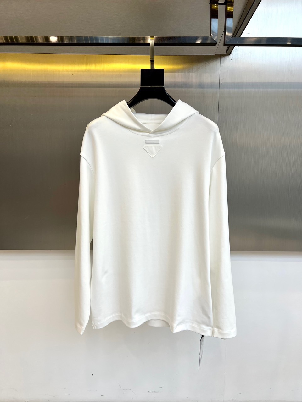 Prad普拉达、2025秋冬新品白色连帽上衣，以极简设计诠释现代奢华运动风范。款式采用宽松立体的剪裁，连