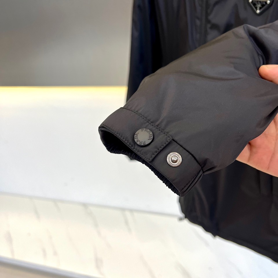 Prada普拉（鹅绒）25ss新款 连帽加厚保暖中长款连帽羽绒服外套，面料采用再生Re-Nylon环保的