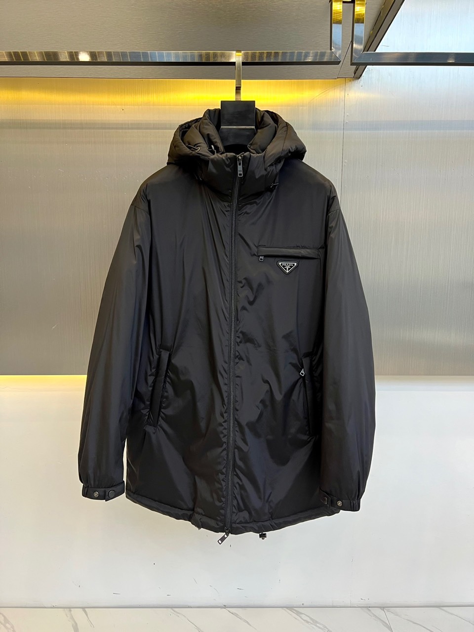 Prada普拉（鹅绒）25ss新款 连帽加厚保暖中长款连帽羽绒服外套，面料采用再生Re-Nylon环保的