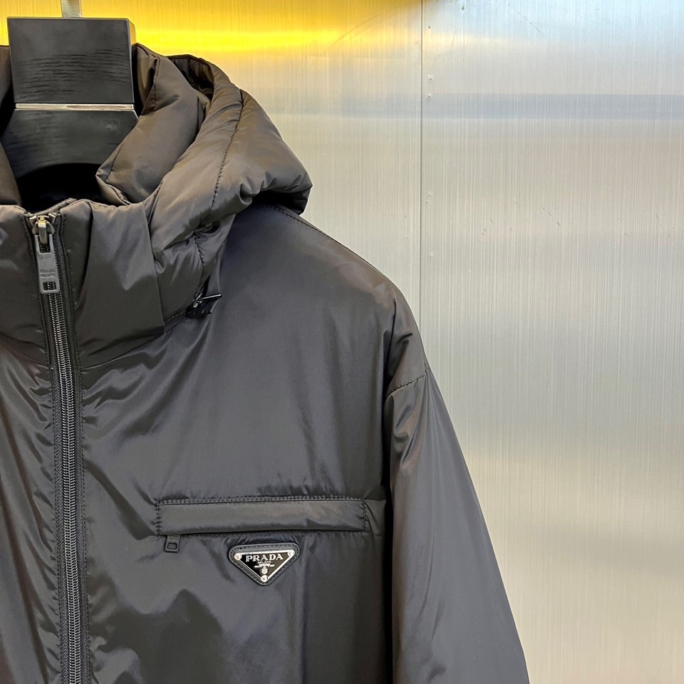 Prada普拉（鹅绒）25ss新款 连帽加厚保暖中长款连帽羽绒服外套，面料采用再生Re-Nylon环保的