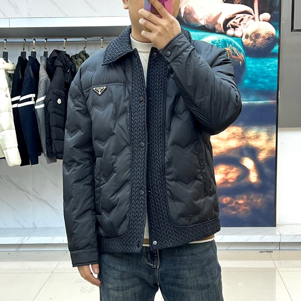 Prad普拉达、2025秋冬新款羽绒服，这款羽绒服采用翻领设计，领口处独特的编织纹理增添细腻质感，搭配品