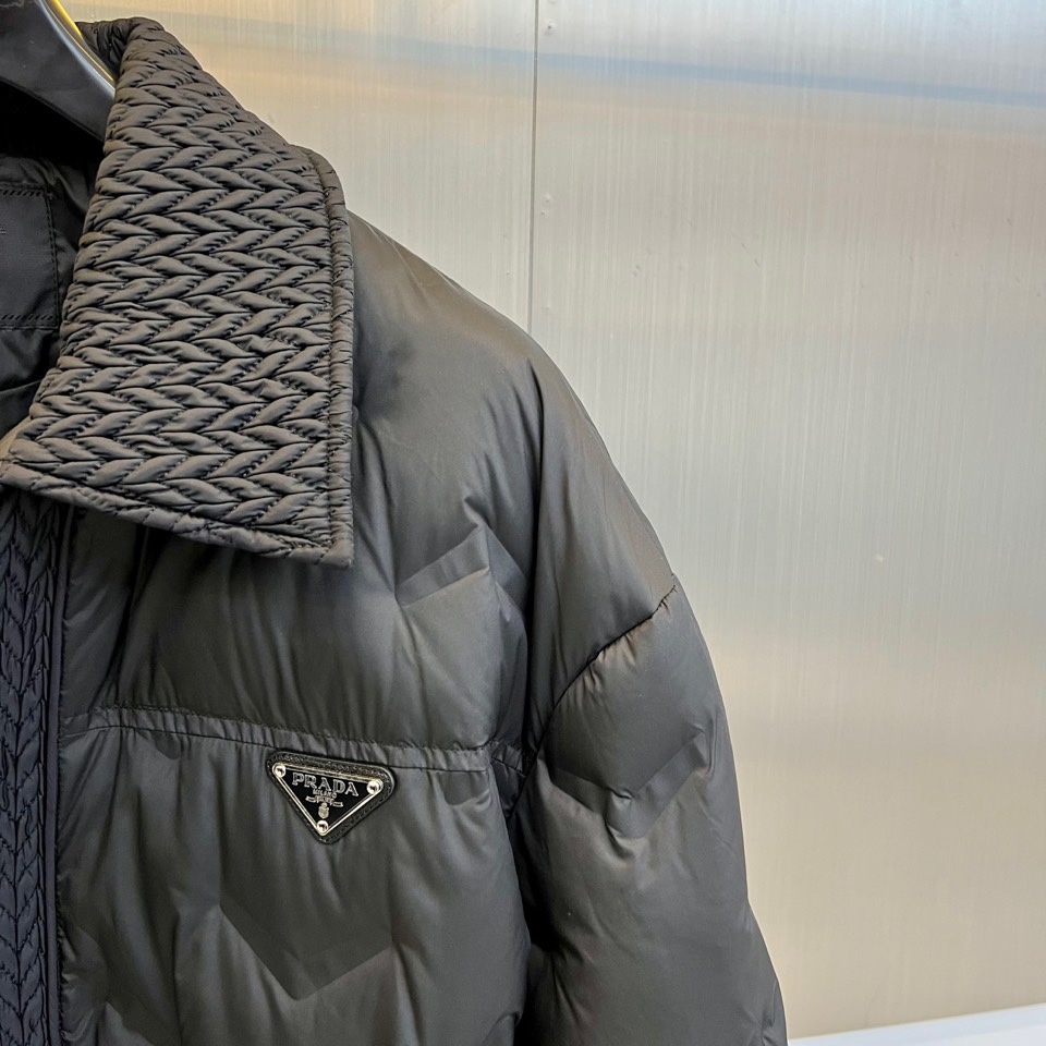 Prad普拉达、2025秋冬新款羽绒服，这款羽绒服采用翻领设计，领口处独特的编织纹理增添细腻质感，搭配品