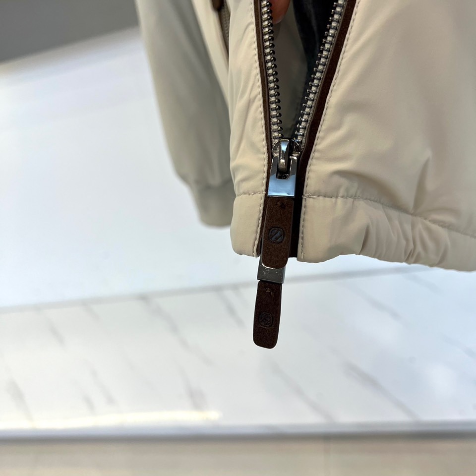 Zegna杰尼亚、2025秋冬新品羽绒服以浅灰质感演绎现代都市美学。这款连帽羽绒服采用极简立体剪裁，前襟