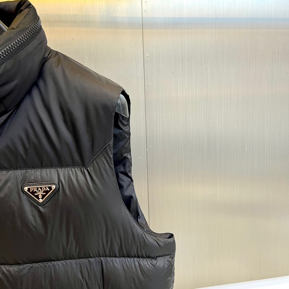 Prad普拉达、2025秋冬新品黑色羽绒马甲以简约设计诠释现代奢华。立领造型搭配顺滑拉链开合，勾勒出利落