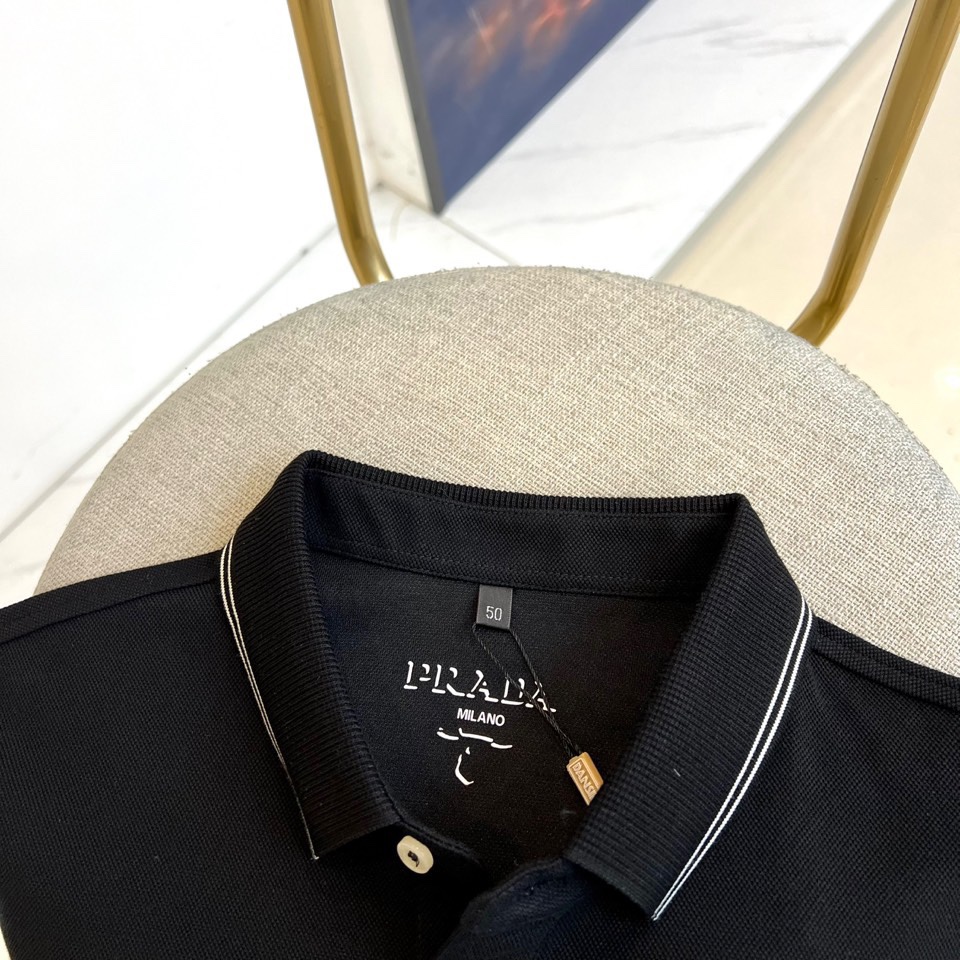Prad普拉达、2025秋冬新品长袖Polo衫，经典翻领设计缀以黑蓝相间条纹边饰，领口下三颗米白色纽扣延