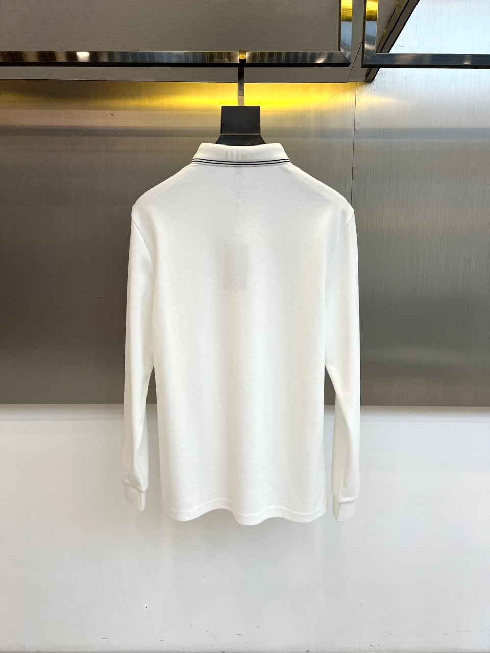 Prad普拉达、2025秋冬新品长袖Polo衫，经典翻领设计缀以黑蓝相间条纹边饰，领口下三颗米白色纽扣延