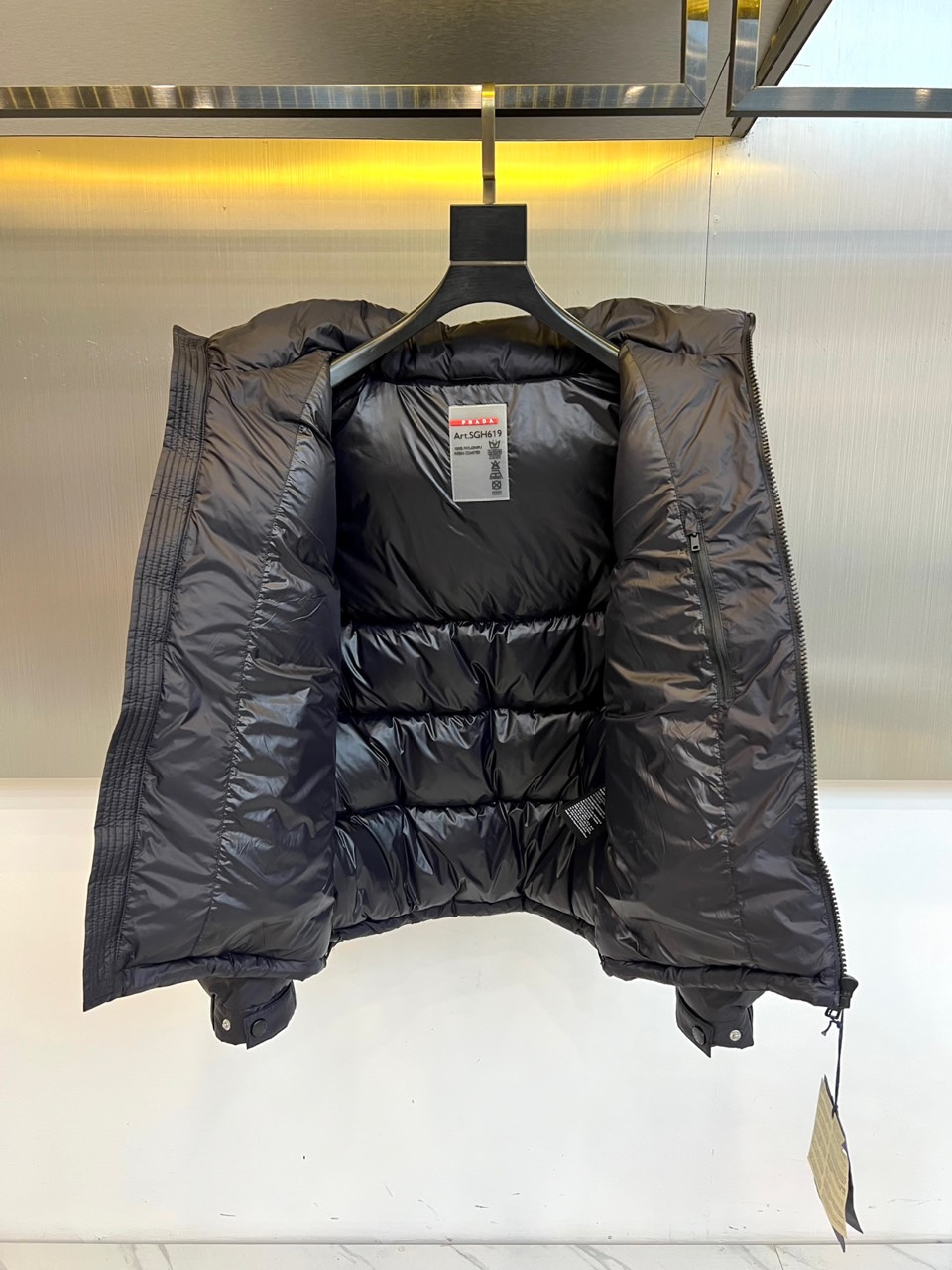 Prad普拉达、2025秋冬新品，黑色羽绒服诠释简约奢华的冬日美学。款式采用流畅的过膝廓形，搭配连帽设计