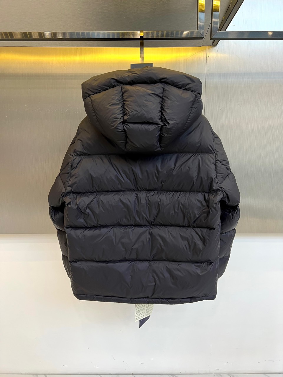 Prad普拉达、2025秋冬新品，黑色羽绒服诠释简约奢华的冬日美学。款式采用流畅的过膝廓形，搭配连帽设计