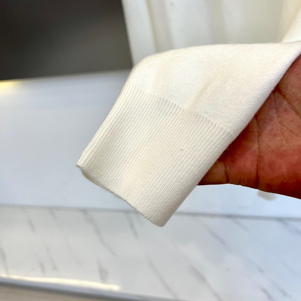 Prad普拉、2025秋冬新品白色针织毛衣，以极简主义美学诠释当代优雅。这款毛衣采用经典圆领设计，左胸位