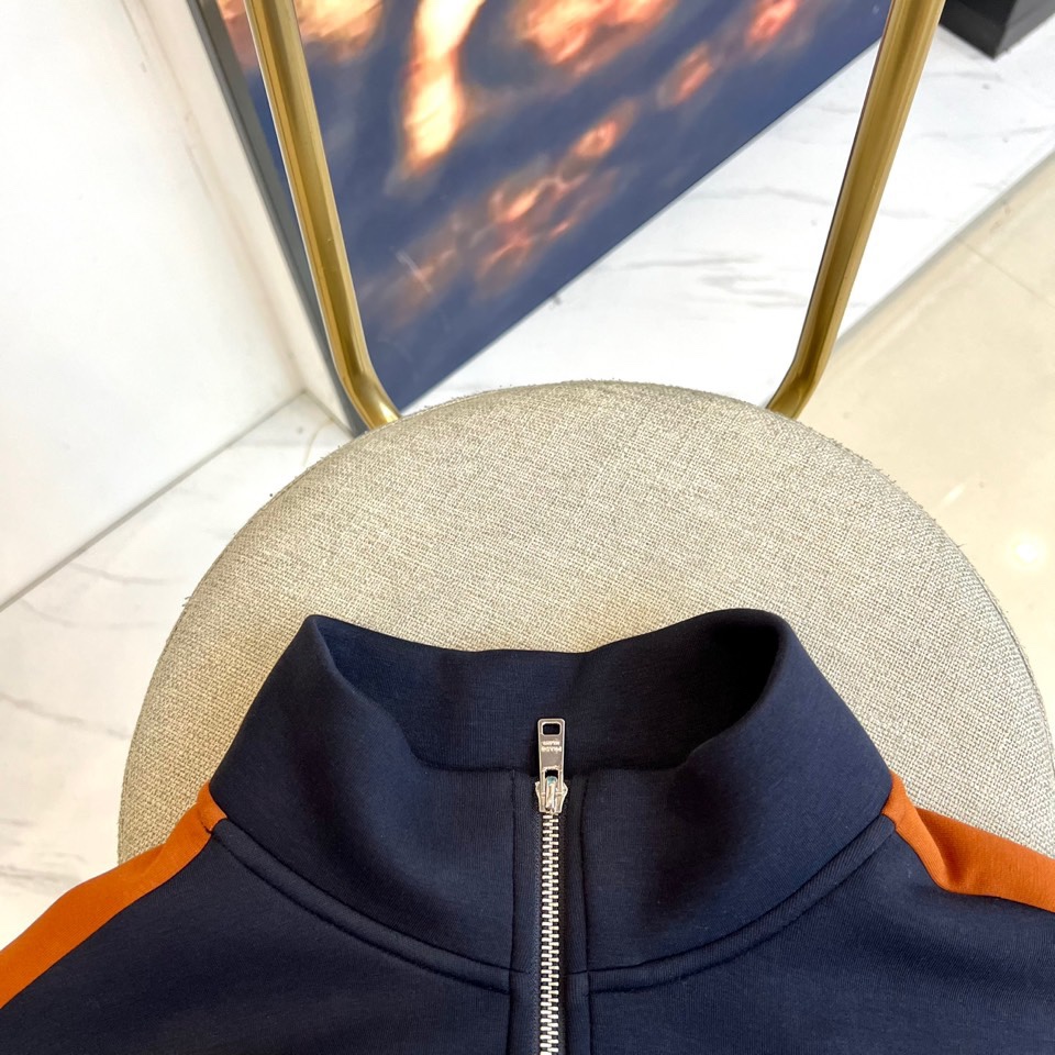 Prad普拉、2025秋冬运动系列。高密弹力面料构筑立体剪裁套装，橙棕条纹如赛道轨迹贯穿袖管与裤线。金属