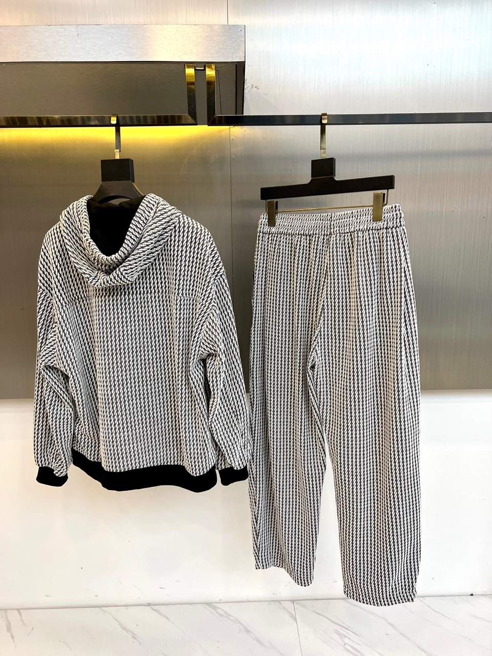 罗意威（LOEWE）套装，以经典的黑白千鸟格纹贯穿始终，将复古优雅与现代时尚感精妙结合。连帽上衣的千鸟格