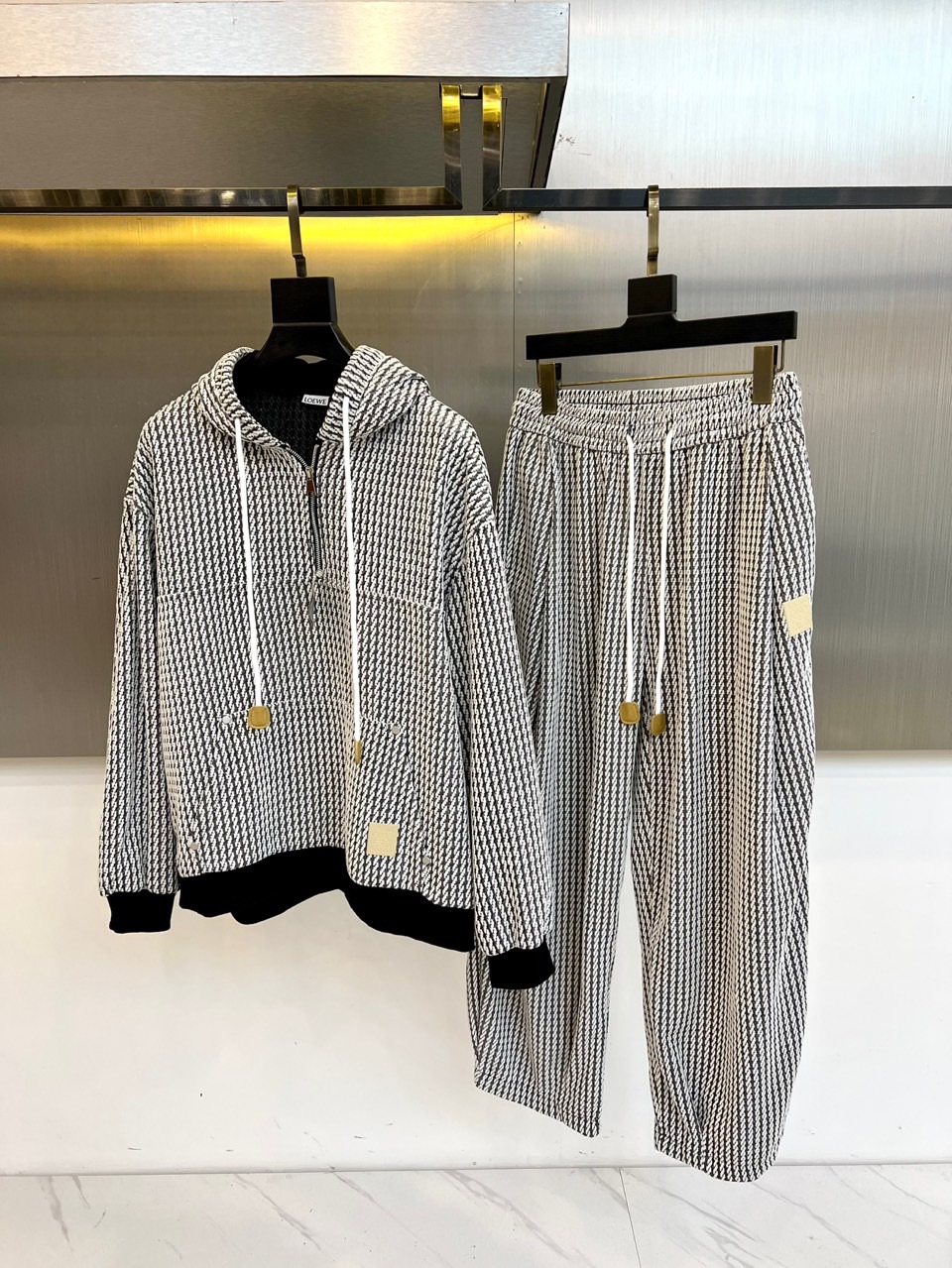 罗意威（LOEWE）套装，以经典的黑白千鸟格纹贯穿始终，将复古优雅与现代时尚感精妙结合。连帽上衣的千鸟格