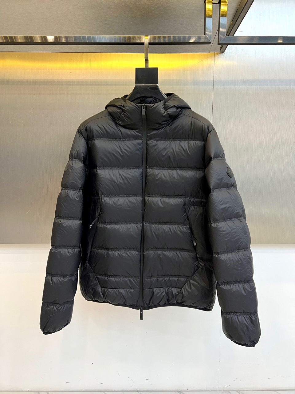 NO:681025,Mon (pure goose down), the new autumn and winter down jacket, interprets urban outdoor aesthetics in classic black. This hooded down jacket uses horizontal quilting technology to outline a three-dimensional silhouette, and the slim fit perfectly fits the body line. The left sleeve is embellished with the brand's iconic emblem, and the front is equipped with a smooth zipper system. The hooded design enhances windproof practicality. The filling strictly follows the USA-certified standards of the United States, using a golden ratio of 90 pure goose down and 10 feathers, 'PURE GOOSE  DOWN' logo highlights the excellent warmth quality. Its design perfectly integrates functionality and fashion sense, and the quilted lines not only ensure the even distribution of down and add visual layering. From urban commuting to suburban activities, this down jacket, with Mengkou's signature exquisite craftsmanship and professional configuration, has become an ideal choice for both temperature and style in cold winter. Sizes 1-5 (model 173, 143 pounds upper body size 2), Moncler, down jacket, gold, hats,19860909Mon蒙口（纯鹅绒）、秋冬新款羽绒服,以经典黑色演绎都市户外美学.这款连帽羽绒服采用横向绗缝工艺勾勒出立体轮廓,修身剪裁完美贴合身形线条.左袖点缀品牌标志性徽章,前襟配置顺滑拉链系统,连帽设计增强防风实用性.填充物严格遵循美国USA-认证标准,采用90纯鹅绒与10羽毛的黄金配比,'PURE GOOSE DOWN'标识彰显卓越保暖品质.其设计将功能性与时尚感完美融合,绗缝线条既确保羽绒均匀分布又增添视觉层次.从城市通勤到郊外活动,这件羽绒服以蒙口标志性的精湛工艺与专业配置,成为寒冬中兼具温度与风度的理想之选.1-5码（模特173,143斤上身2码）,,Moncler,down jacket,gold,hats,,Men's clothing