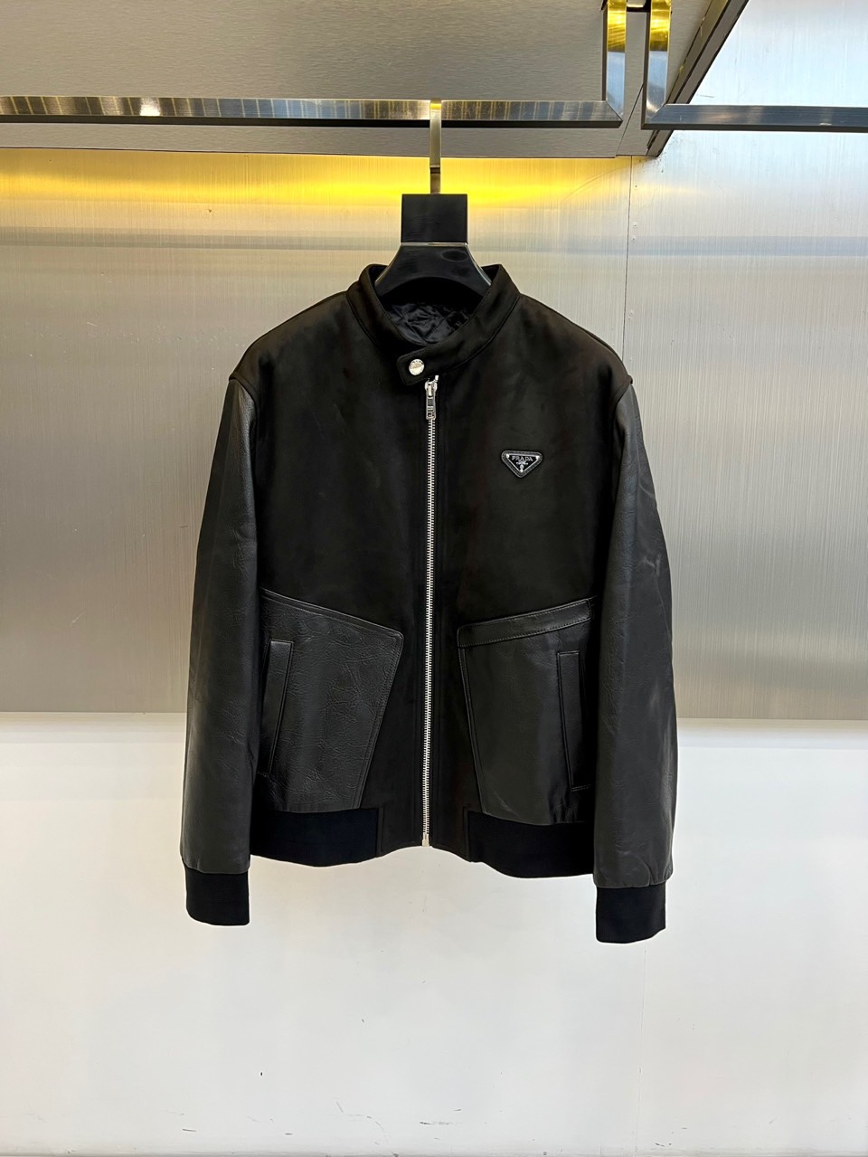 Prad普拉、2025秋冬新品 PRADA麂皮拼接夹克。这款夹克以复古摩登为设计基调，采用立领设计搭配金