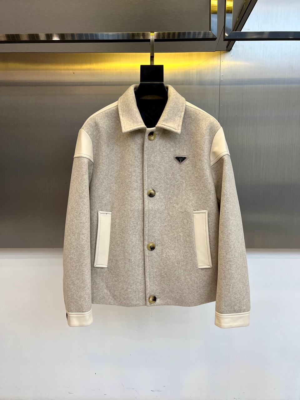 NO:681033,Prad, new products for autumn and winter  PRADA quilted craft jacket, this jacket has a stand-up collar design with a metal zipper opening and closing system, and the body uses precise diamond quilting technology to outline a three-dimensional silhouette. The left chest is embellished with the brand's iconic triangular enamel logo, and the diagonal pockets on both sides have both practical functions and line aesthetics. The fabric is made of 82.1 nylon and 17.9 spandex in a scientific ratio. The nylon component ensures that the fabric is stiff and wear-resistant, and the spandex gives moderate elasticity; the lining is made of polyester fiber to ensure smooth wear.  Degree. The main tone of light gray shows a sense of layering through the collision of materials, and the leather decorative edges enhance the overall texture. It can be paired with suit pants to create a business casual style, or with casual pants to create an urban daily look. Through the combination of quilting technology and technical fabrics, PRADA's design philosophy of integrating Italian aesthetics and practical functions is interpreted. 48-56 (model 173, 143 pounds, upper body size 50),, prada, prada, jackets  & coats,business suits,19860909Prad普拉、秋冬新品 PRADA绗缝工艺夹克,这款夹克采用立领设计搭配金属拉链开合系统,衣身运用精准的菱形绗缝工艺勾勒立体轮廓.左胸点缀品牌标志性三角形珐琅徽标,两侧斜插口袋兼具实用功能与线条美感.面料选用82.1锦纶与17.9氨纶科学配比,锦纶成分保证面料挺括耐磨,氨纶赋予适度弹性；衬里采用聚酯纤维确保穿着顺滑度.浅灰主调通过材质碰撞展现层次感,皮革装饰边沿提升整体质感.既可搭配西装裤演绎商务休闲风范,也能搭配休闲裤打造都市日常造型.通过绗缝工艺与科技面料的结合,诠释PRADA将意式美学与实用功能相融合的设计哲学.48-56（模特173,143斤上身50码）,,prada,prada,jackets & coats,business suit,,Men's clothing