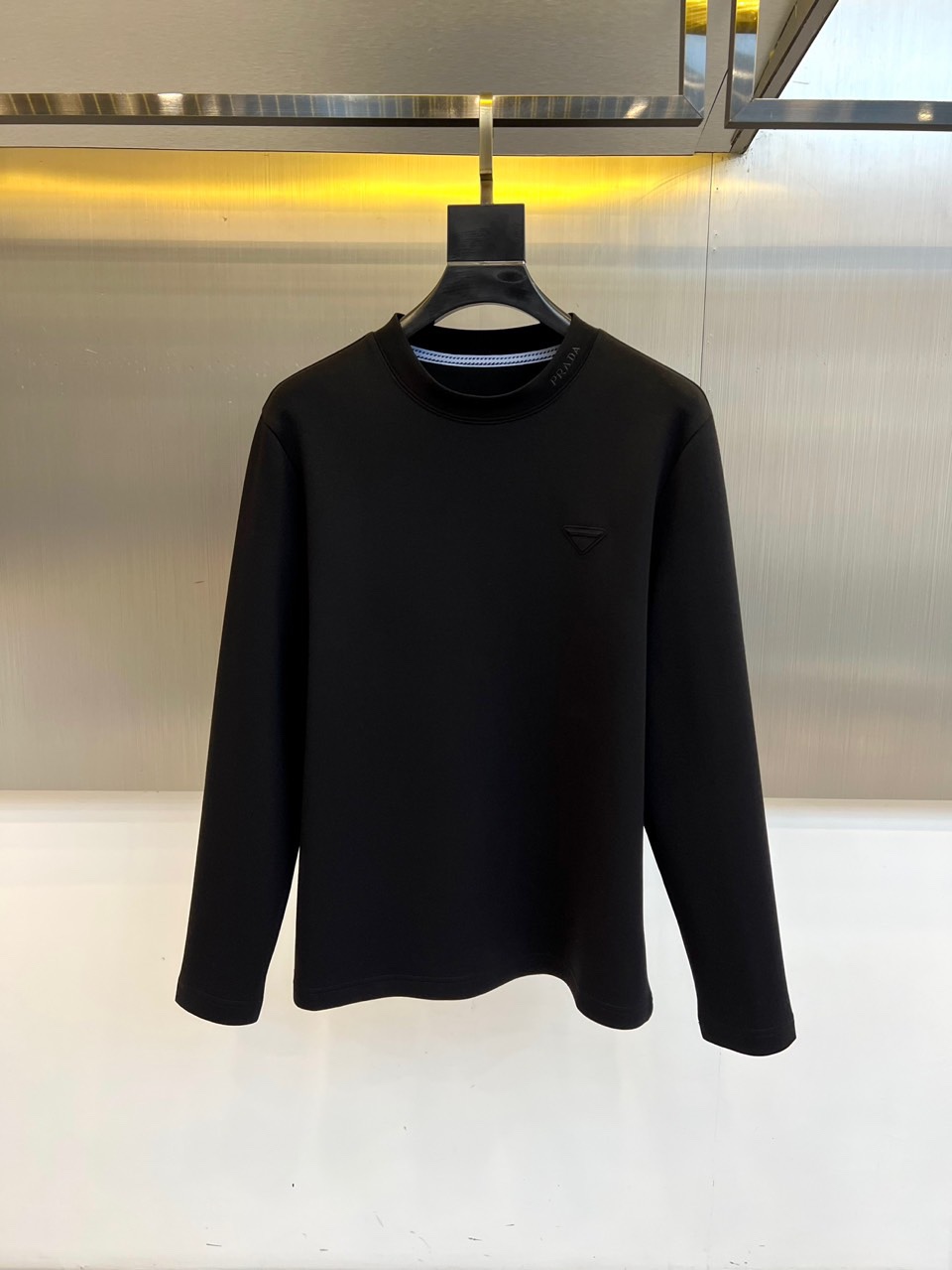 NO:681045,Prad, the new men's white long-sleeved T-shirt for autumn and winter, interprets modern luxury with minimalist aesthetics. This product is made of 320g modal air-layer fabric, which contains a scientific ratio of regenerated cellulose fiber, cotton, polyester fiber and spandex to achieve the perfect balance of softness, skin-friendly and stiff warmth. The classic round neck design is lined with blue and white striped details, and the three-dimensional triangle logo on the left chest low-key highlights the brand genes. The slim cut ensures that the hem hangs naturally and has a simple silhouette without unnecessary decoration.  High-end texture and practical wearability. The pure white color shows adaptability to multiple scenes. It can be worn alone to show a refreshing and neat urban style, or can be worn perfectly as an inner layer with suits and jackets. Prada uses exquisite craftsmanship and contemporary design language to reshape daily basic models into must-have items that combine comfort and luxury to meet the all-round needs of modern gentlemen for quality life. M-4XL (model 173, 143 pounds, upper body size L),, prada, prada, jackets  & coats,tees,t-shirt,business suit,19860909Prad普拉达、秋冬新品男士白色长袖T恤,以极简主义美学诠释现代奢华.本品采用320克莫代尔空气层面料,含再生纤维素纤维、棉、聚酯纤维与氨纶的科学配比,实现柔软亲肤与挺括保暖的完美平衡.经典圆领设计内衬蓝白相间条纹细节,左胸处的立体三角形标志低调彰显品牌基因.修身剪裁确保衣摆自然垂坠,无多余装饰的简约廓形兼具高级质感与实穿性.纯白色调呈现多场景适配性,既可单穿展现清爽利落的都市风格,亦能作为内搭与西装、外套完美叠穿.普拉达以精湛工艺与当代设计语言,将日常基础款重塑为兼具舒适度与奢华感的必备单品,满足现代绅士对品质生活的全方位需求.M-4XL（模特173,143斤上身L码）,,prada,prada,jackets & coats,tees，t-shirt,business suit,,Men's clothing