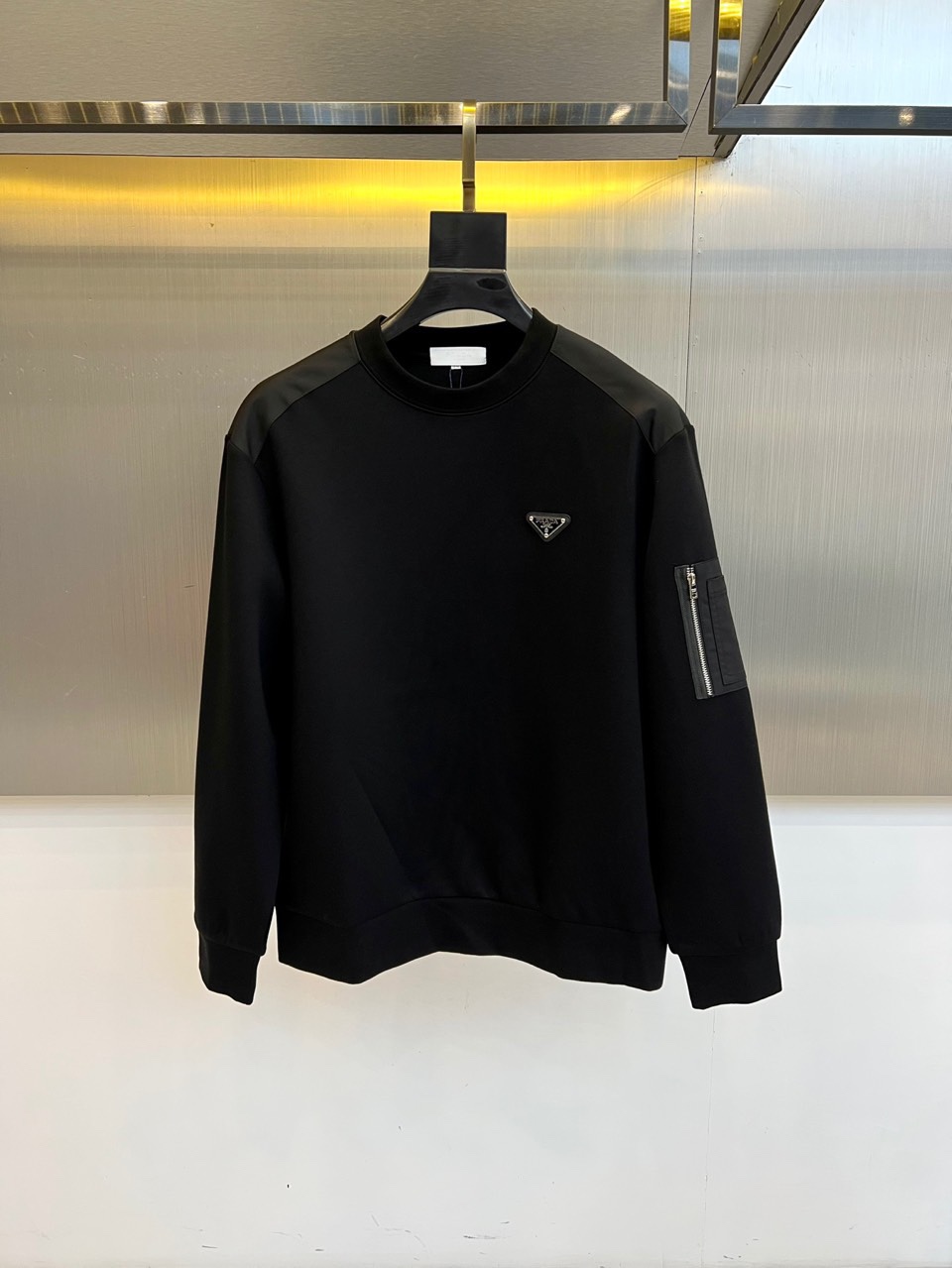 Prad普拉、2025秋冬新品 | PRADA极简卫衣。这款圆领卫衣采用微阔版型设计，左胸点缀品牌标志性