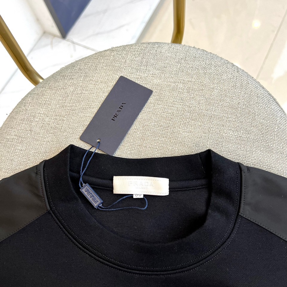 Prad普拉、2025秋冬新品 | PRADA极简卫衣。这款圆领卫衣采用微阔版型设计，左胸点缀品牌标志性