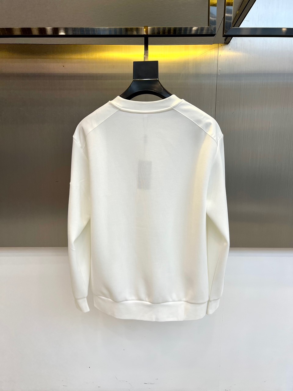 Prad普拉、2025秋冬新品 | PRADA极简卫衣。这款圆领卫衣采用微阔版型设计，左胸点缀品牌标志性