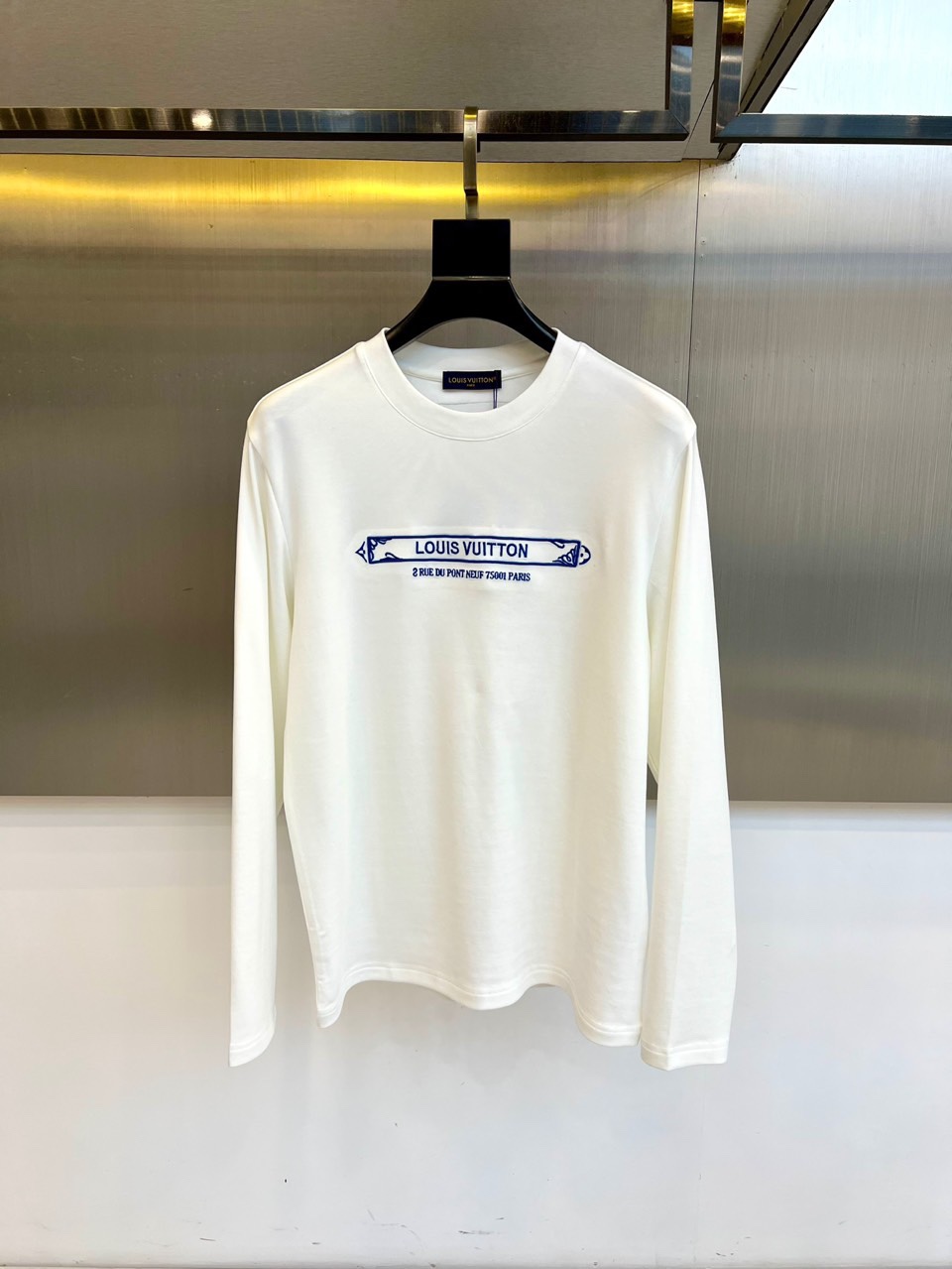 NO:681004,1v Vuitton's new long-sleeved T-shirt for autumn and winter interprets modern luxury with minimalist design. The style adopts a classic slim fit and is made of high-quality pure cotton fabrics to create a soft and skin-friendly wearing experience. The blue ribbon decorated on the chest becomes the highlight of the design, with the brand logo and legendary address '2 RUE DU PONT NEUF 75001' carefully embroidered on it.  PARIS', highlighting Louis Vuitton's profound brand heritage. The style perfectly balances leisure and luxury, with pure white tone and exquisite details. It can be worn alone to show simple fashion, or as an inner layer to create a layered look. This T-shirt elevates daily items to the realm of high fashion, whether it is paired with jeans to create a casual style, or paired with a suit jacket for business casual  look, can show extraordinary taste. The Paris address logo in the details pays tribute to the birthplace of the brand, giving the single product unique cultural connotation. As a must-have basic model for the autumn and winter wardrobe, it shows Louis Vuitton's exquisite craftsmanship and fashion attitude in a low-key way, making simple wear full of luxurious texture. 48-56 (model is 173, 143 pounds, upper body size 50),, louis  vuitton,jeans,jackets & coats,tees,t-shirt,business suit,198609091v威登、秋冬新品长袖T恤,以极简设计诠释现代奢华.款式采用经典修身剪裁,精选高品质纯棉面料打造柔软亲肤的穿着体验.胸前装饰的蓝色织带成为设计亮点,其上精心绣有品牌标识与传奇地址'2 RUE DU PONT NEUF 75001 PARIS',彰显路易威登深厚的品牌传承.风格上完美平衡休闲与奢华感,纯净白色基调搭配精致细节,既能单穿展现简约时尚,也可作为内搭打造层次造型.这款T恤将日常单品提升至高级时尚领域,无论是搭配牛仔裤营造休闲风格,还是搭配西装外套演绎商务休闲look,都能展现不凡品味.细节处的巴黎地址标识致敬品牌发源地,赋予单品独特文化内涵.作为秋冬衣橱的必备基础款,它以低调方式展现路易威登的精湛工艺与时尚态度,让简约穿着也充满奢华质感.48-56（模特173,143斤上身50码）,,louis vuitton,jeans,jackets & coats,tees，t-shirt,business suit,,Men's clothing