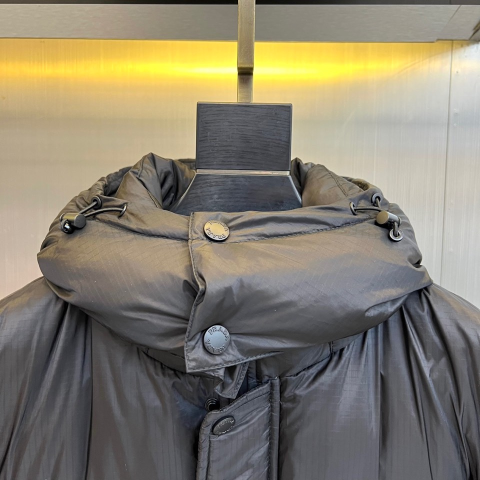 Prad普拉达、2025秋冬黑色羽绒服，以标志性设计语言重塑冬日温暖。款式采用宽松休闲的连帽廓形，帽檐配