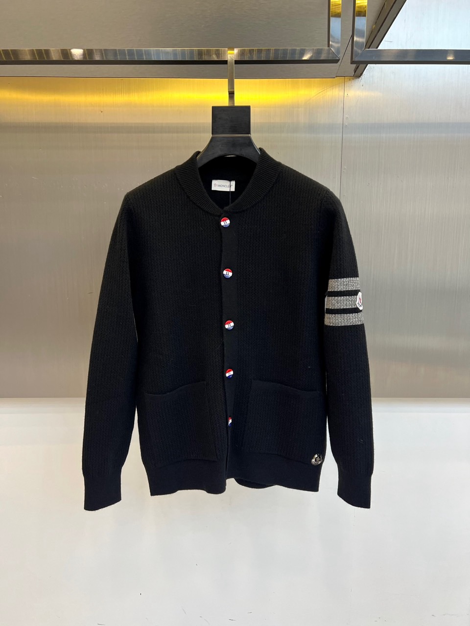 蒙口、2025秋冬新品以经典灰色针织开衫诠释休闲奢雅。标志性的棒球领设计，兼具利落与活力。前襟整齐排列的