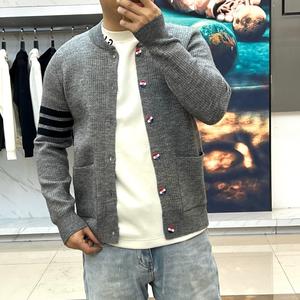 蒙口、2025秋冬新品以经典灰色针织开衫诠释休闲奢雅。标志性的棒球领设计，兼具利落与活力。前襟整齐排列的