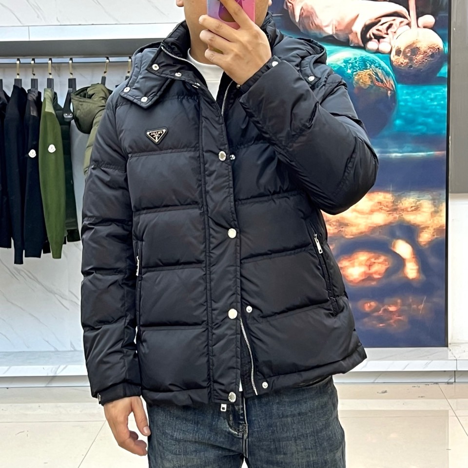 Prad普拉达、2025秋冬新品男士羽绒服，以深邃藏青色演绎现代都市的摩登型格。这件外套采用经典的箱型轮
