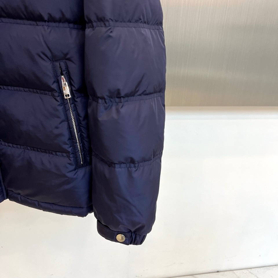 Prad普拉达、2025秋冬新品男士羽绒服，以深邃藏青色演绎现代都市的摩登型格。这件外套采用经典的箱型轮