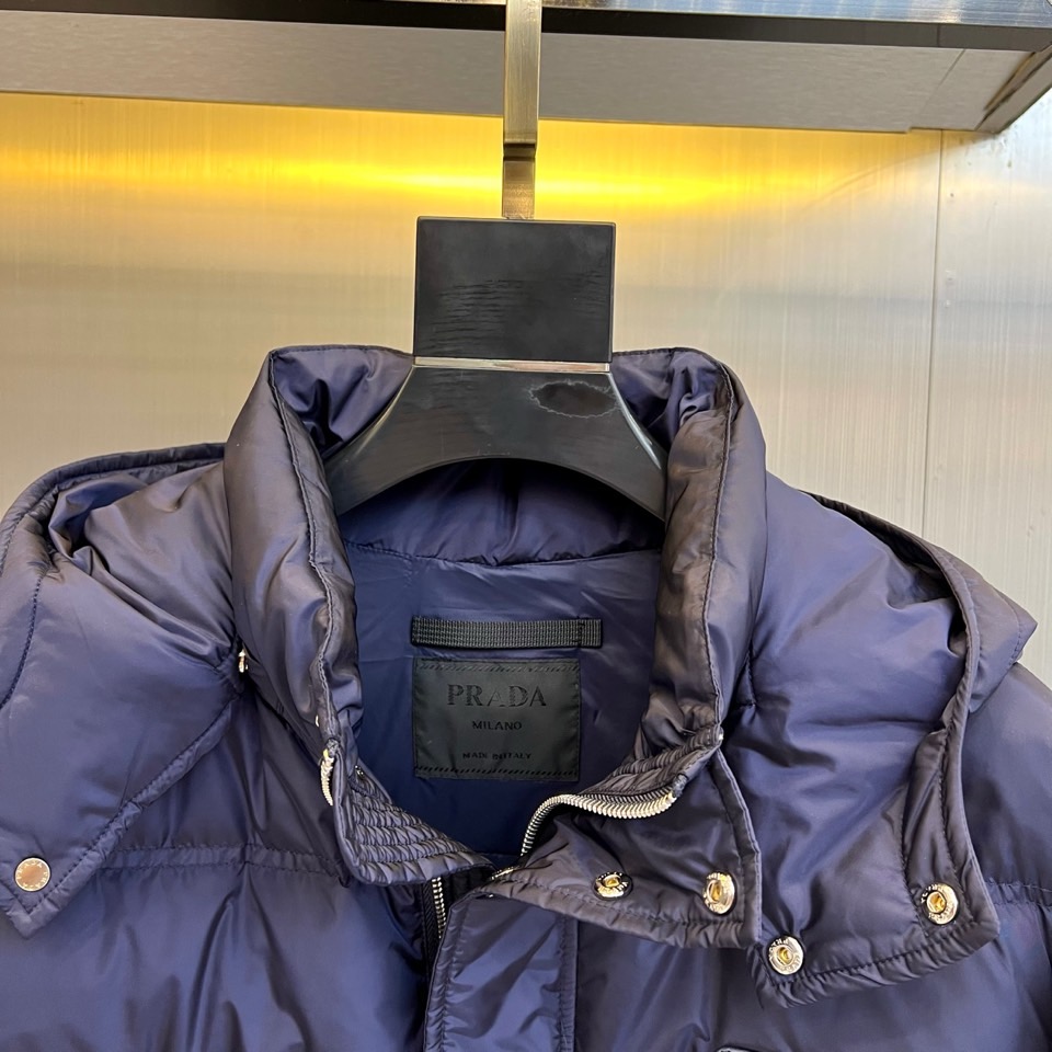 Prad普拉达、2025秋冬新品男士羽绒服，以深邃藏青色演绎现代都市的摩登型格。这件外套采用经典的箱型轮