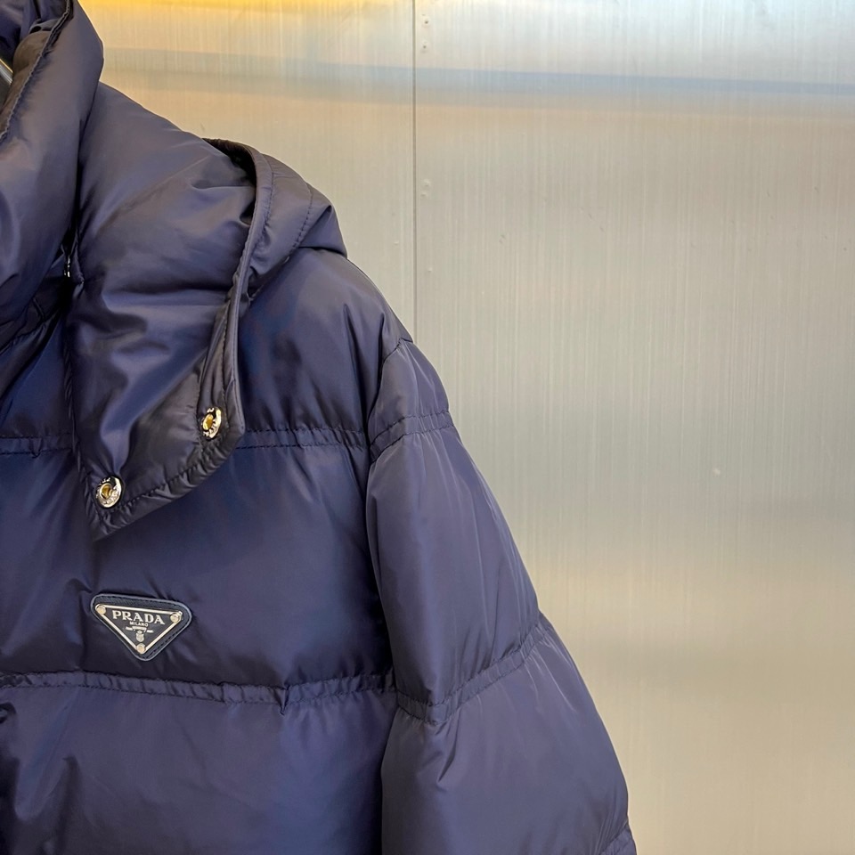 Prad普拉达、2025秋冬新品男士羽绒服，以深邃藏青色演绎现代都市的摩登型格。这件外套采用经典的箱型轮