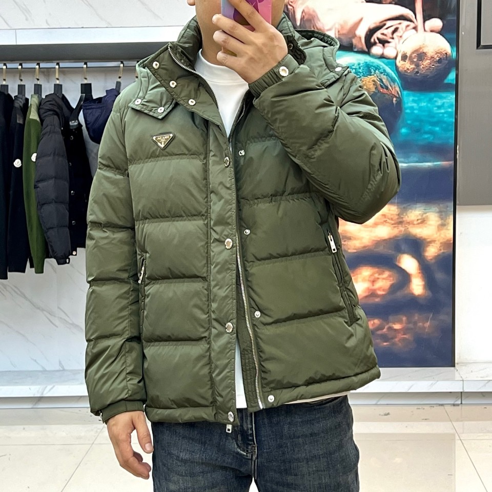 Prad普拉达、2025秋冬新品男士羽绒服，以深邃藏青色演绎现代都市的摩登型格。这件外套采用经典的箱型轮