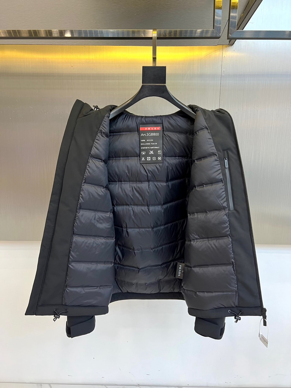 Prad普拉、2025秋冬黑色羽绒服，以品牌标志性设计语言重塑冬日型格。款式采用简约的连帽廓形，线条流畅