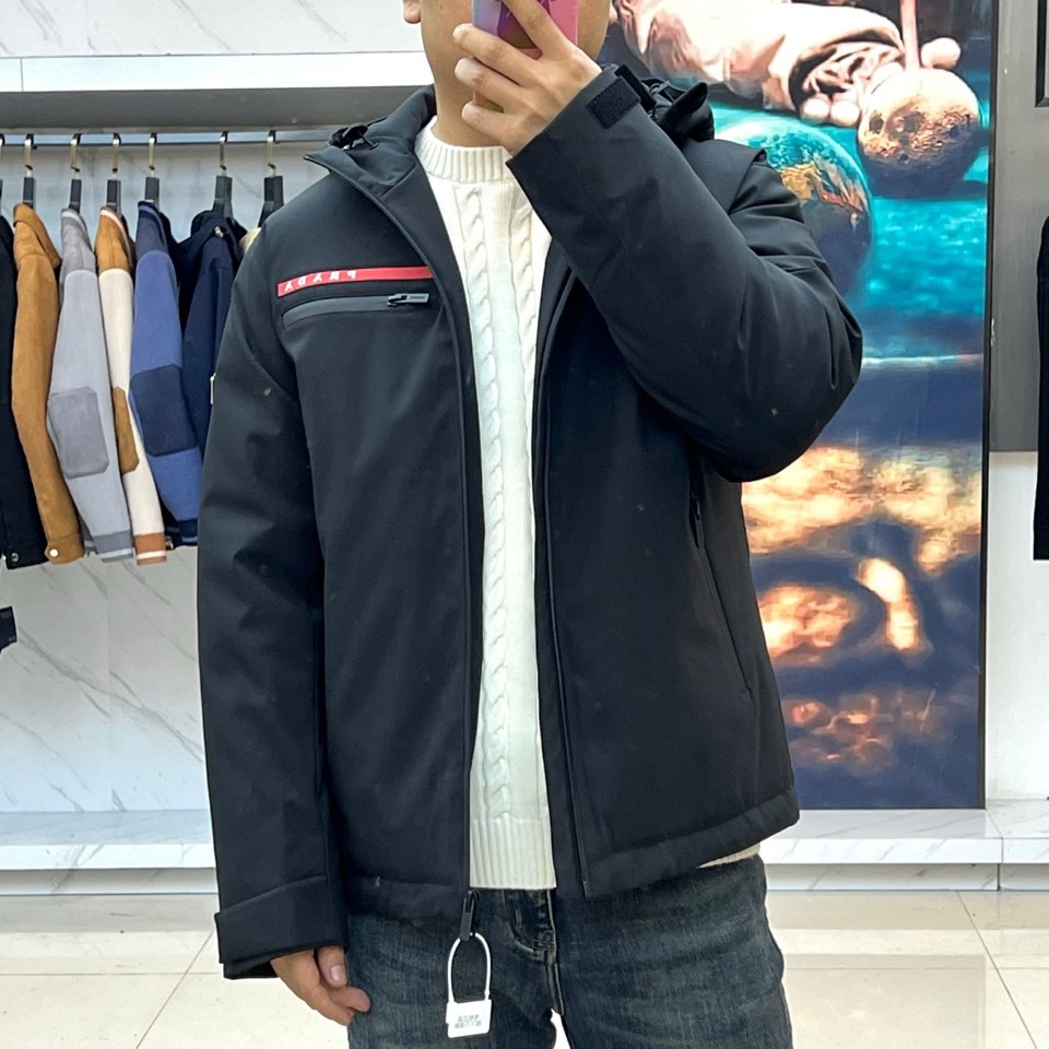 Prad普拉、2025秋冬黑色羽绒服，以品牌标志性设计语言重塑冬日型格。款式采用简约的连帽廓形，线条流畅