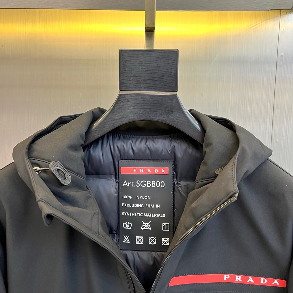 Prad普拉、2025秋冬黑色羽绒服，以品牌标志性设计语言重塑冬日型格。款式采用简约的连帽廓形，线条流畅