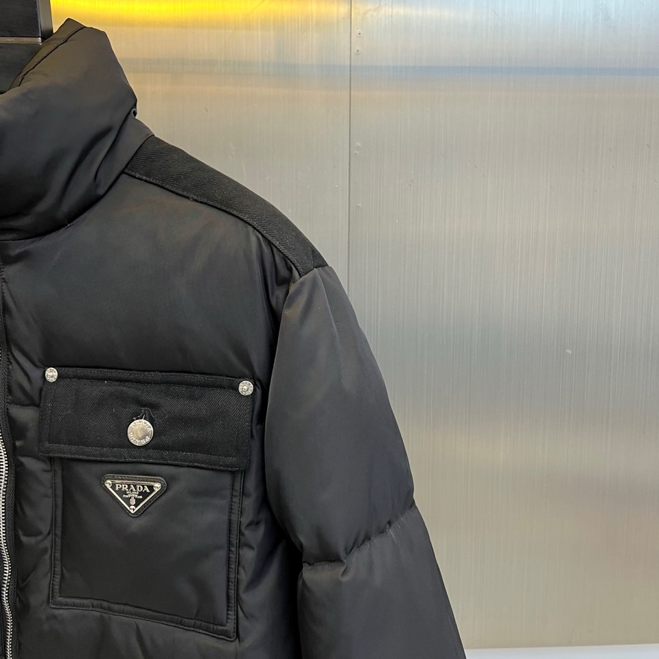 Prad普拉达、2025秋冬新品羽绒服，以纯黑色调演绎现代极简美学。款式采用利落立领设计，搭配银色拉链开