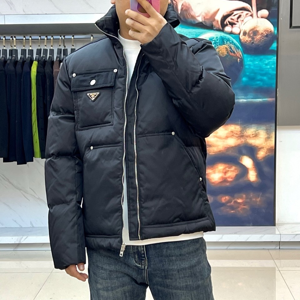 Prad普拉达、2025秋冬新品羽绒服，以纯黑色调演绎现代极简美学。款式采用利落立领设计，搭配银色拉链开