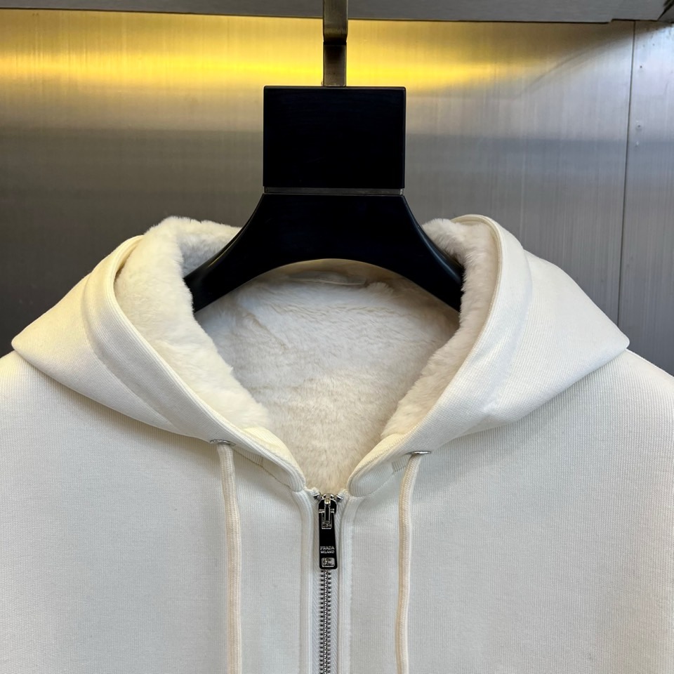 Prad普拉、2025秋冬新品连帽毛绒保暖外套，以极简主义诠释实用美学。这款外套采用立体剪裁的连帽设计，