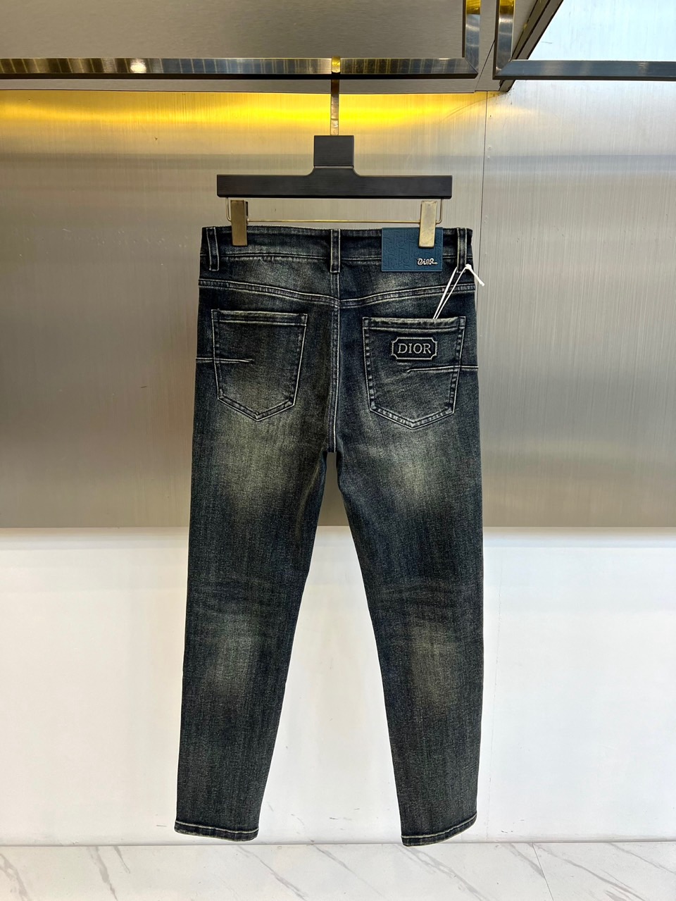 DIO迪奥、2025秋冬新品男士牛仔裤，以深灰色水洗牛仔布演绎现代奢华风尚。直筒剪裁呈现经典版型，后袋装