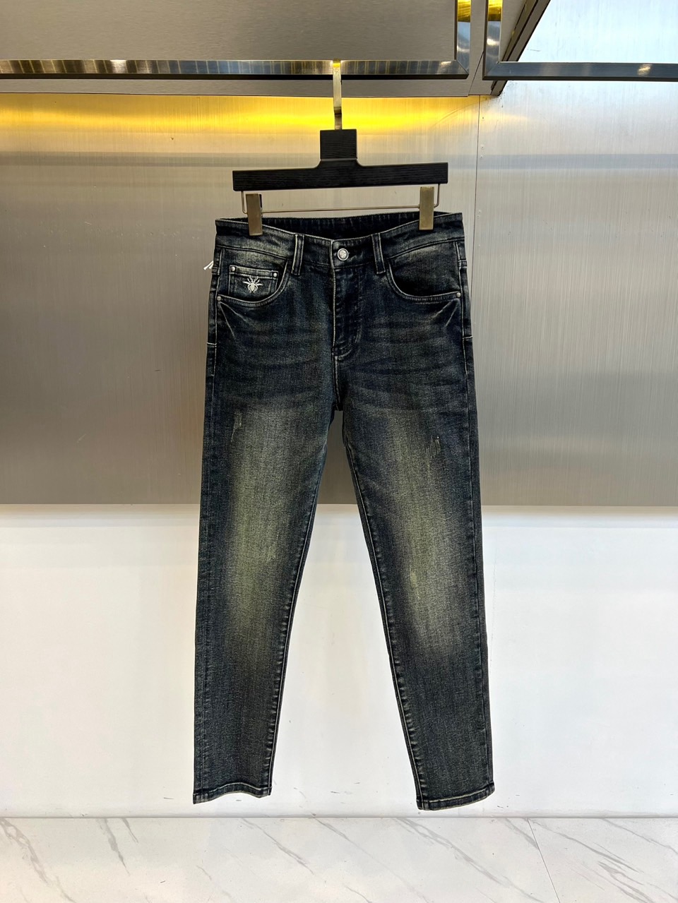 DIO迪奥、2025秋冬新品男士牛仔裤，以深灰色水洗牛仔布演绎现代奢华风尚。直筒剪裁呈现经典版型，后袋装