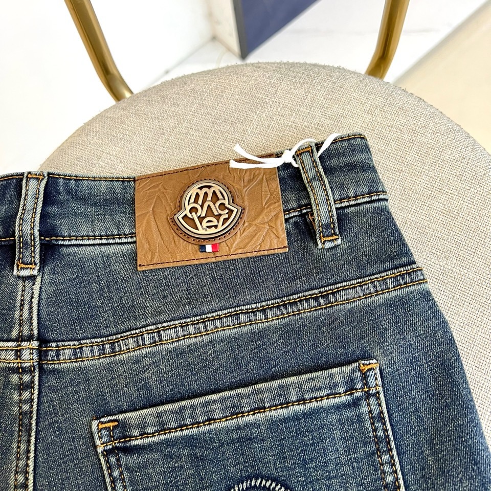 Mon蒙口、2025秋冬新品深蓝色牛仔裤以经典直筒版型演绎现代休闲美学。后袋饰以品牌标志性刺绣徽章，细腻