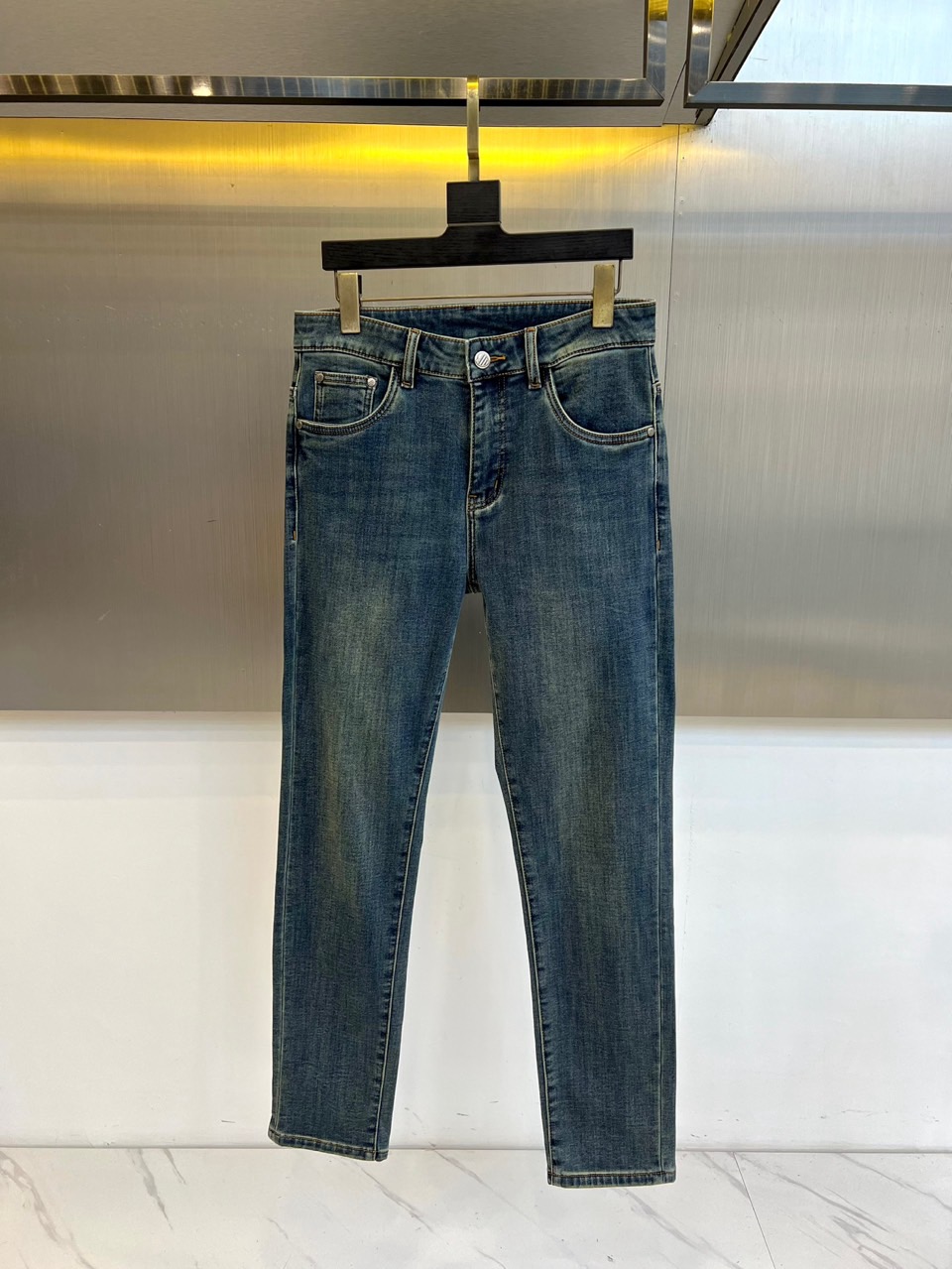 Mon蒙口、2025秋冬新品深蓝色牛仔裤以经典直筒版型演绎现代休闲美学。后袋饰以品牌标志性刺绣徽章，细腻