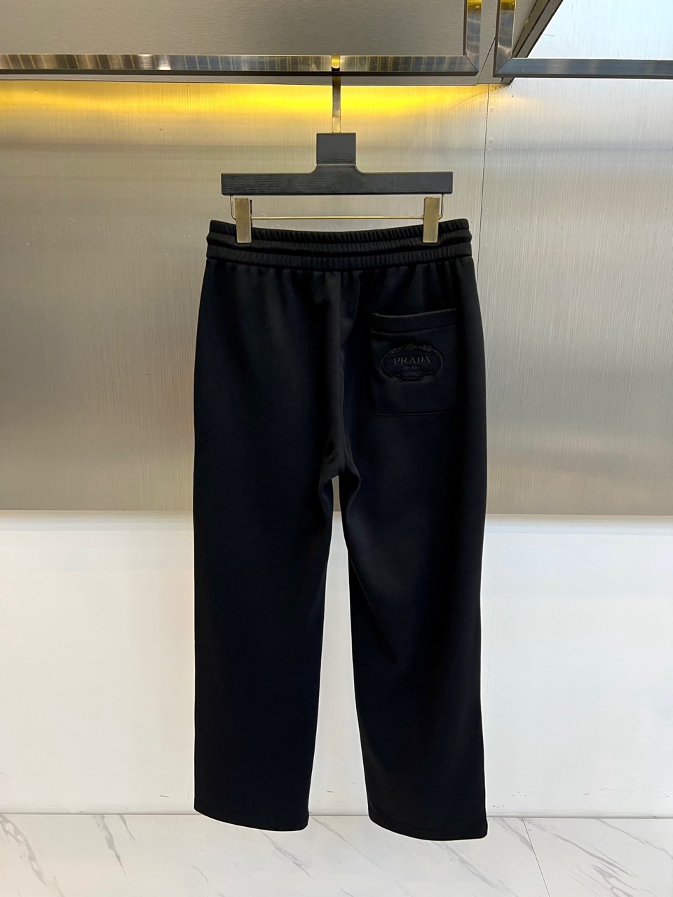 Prad普拉达、2025秋冬新品加绒休闲卫裤，以简约流畅的直筒剪裁，诠释当代休闲服饰的高级质感。裤腰采用