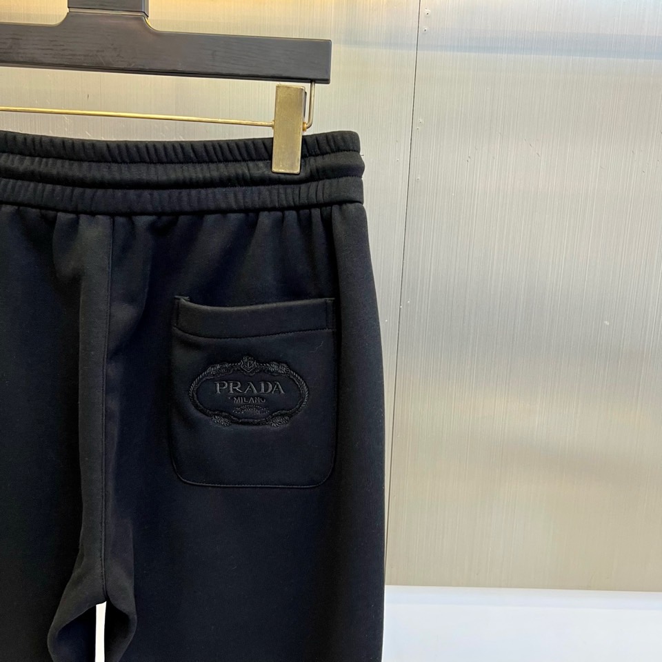 Prad普拉达、2025秋冬新品加绒休闲卫裤，以简约流畅的直筒剪裁，诠释当代休闲服饰的高级质感。裤腰采用