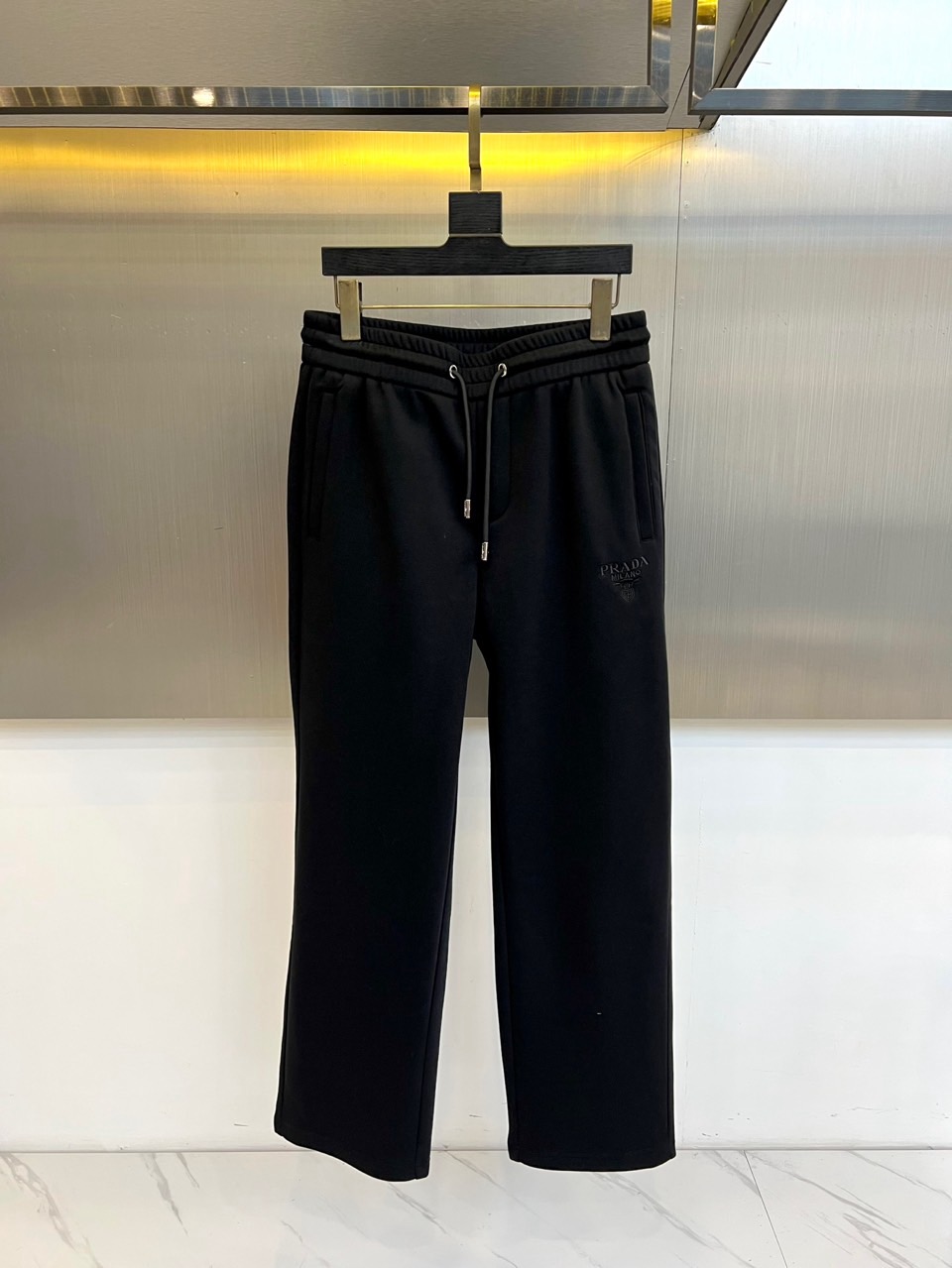 Prad普拉达、2025秋冬新品加绒休闲卫裤，以简约流畅的直筒剪裁，诠释当代休闲服饰的高级质感。裤腰采用