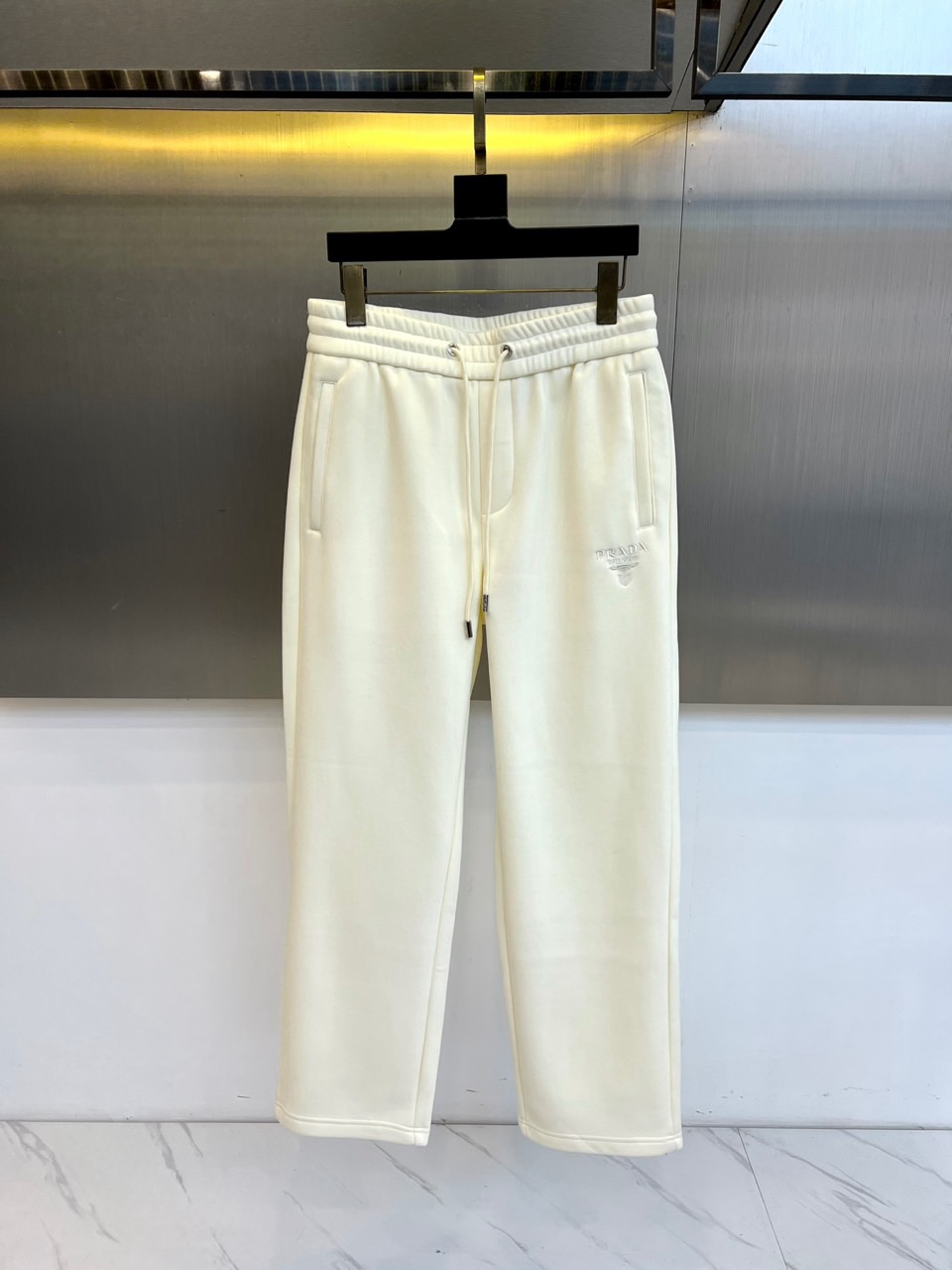 Prad普拉达、2025秋冬新品加绒休闲卫裤，以简约流畅的直筒剪裁，诠释当代休闲服饰的高级质感。裤腰采用
